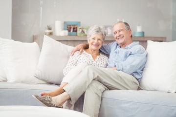 Portrait of romantic senior couple sitting on sofa in living room at home - obrazy, fototapety, plakaty