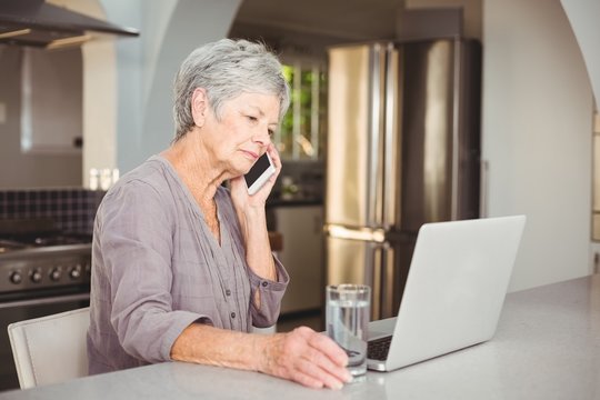 Serious Senior Woman Talking On Mobile Phone