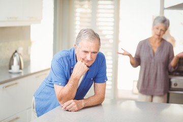 Senior man with woman arguing in background