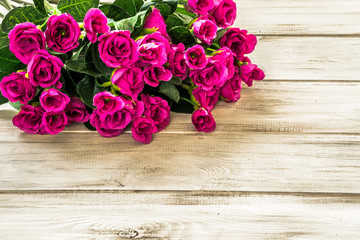 Pink roses flowers arranged on wood background.