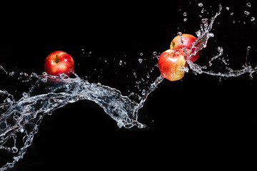 Few red apples apple flying in space with the water on a black background