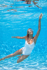 femme qui nage sous l'eau avec un masque dans une piscine