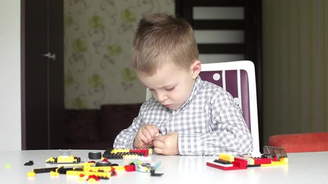 Seroius boy trying to detach bricks of children's building kit then smiling that he can't do it