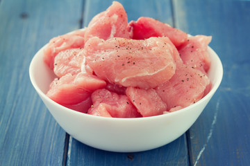 raw turkey on white dish on blue wooden background