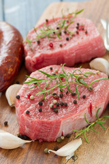 raw meat with smoked sausage, pepper and garlic on wooden board