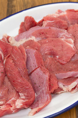 raw turkey on white dish on brown wooden background