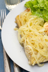 codfish with onion and mashed potato on white plate