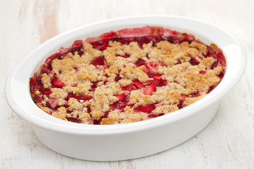 oatmeal strawberry crumble in white dish on white wooden background
