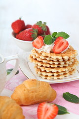 Delicious breakfast with croissants, waffles and fresh strawberr