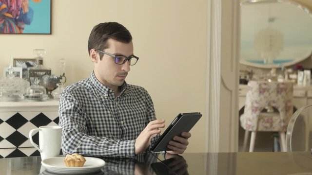 A Young Man Looks Through His Tablet as He Hakes.