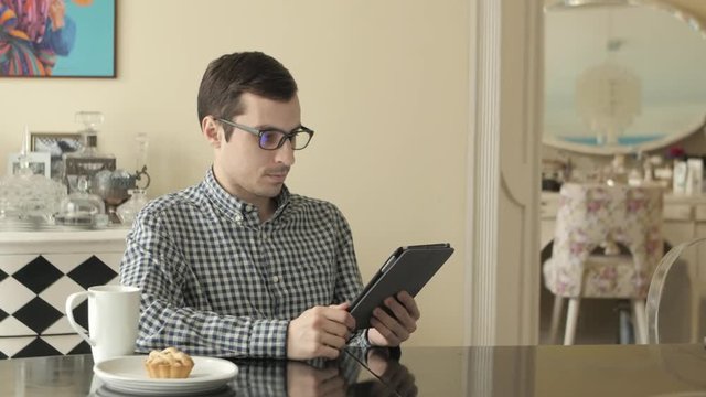 A Young Man Looks Through His Tablet as He Hakes.