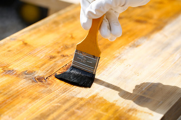 Painter painting wooden surface, protecting wood - 108029210