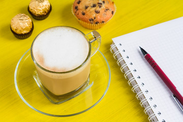 Coffee  with notebook on a yellow table