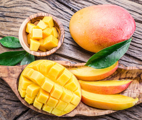Mango fruit and mango cubes on the wooden table.