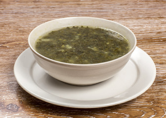 Traditional green dietary  soup in a bowl on wooden background