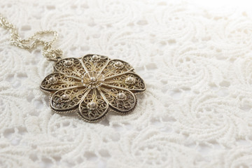 Beautiful vintage old female jewelry pendant on crochet lace background
