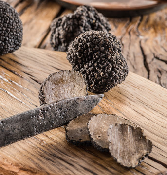 Cutting of black truffle on the wooden board.