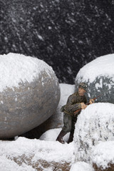 miniature toy soldier standing on snowy rocks
