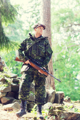 young soldier or hunter with gun in forest