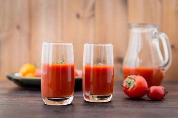 Fototapeta na wymiar Glass of tomato juice with vegetables on old wooden background, with greenery and tomatoes