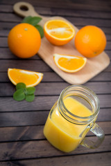 Freshly squeezed orange juice in glass, with fruits on wooden background