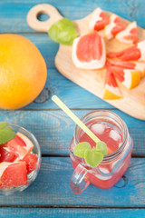 Freshly squeezed orange and grapefruit juice in glass, with fruits on wooden background