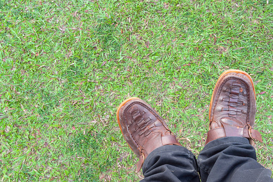 green grass,Old shoes, brown boots  and  black pants. grass on background