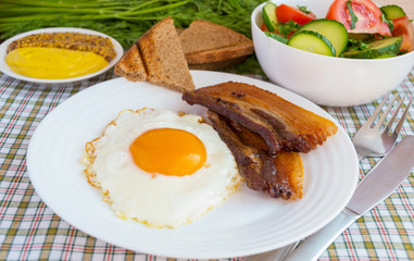 Scrambled eggs with bacon on a white plate. Breakfast.