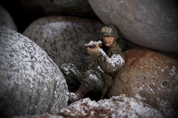 miniature toy soldier figure leaning on rocks