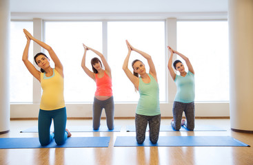 happy pregnant women exercising on mats in gym