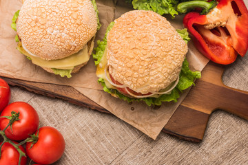 Two homemade vegetarian burgers with fresh organic vegetables on rustic wooden background
