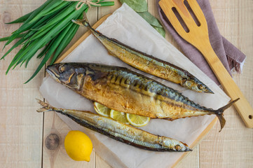 Baked sea fish (saury, mackerel) on wooden background. The top view.