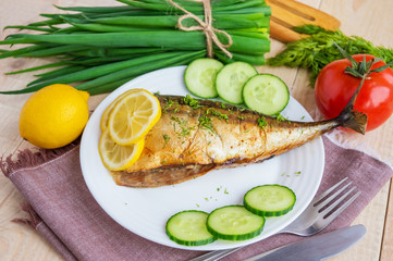Baked sea fish ( mackerel) on wooden background. The top view.