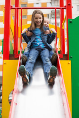 Girls slides down the hill on the playground