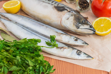 Marine fish (mackerel, saury) and spices on wooden background