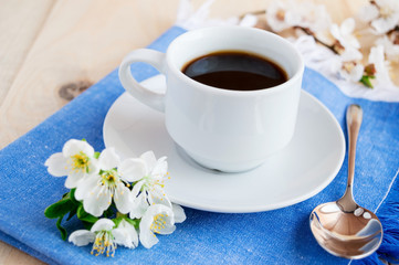 Cup of coffee on a blue napkin. Spring flowers. 