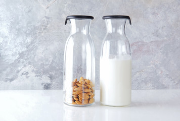 fresh homemade almond milk in a transparent bottle and almonds.