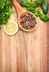 Spices, lemon, parsley and basil in spoons on wooden background