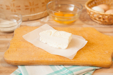 Butter on parchment on cutting board and towel, eggs, raw eggs, salt on background on light wooden table.