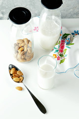fresh homemade almond milk in a transparent bottle and almonds.