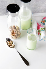 fresh homemade pistachio milk in a transparent bottle and pistac