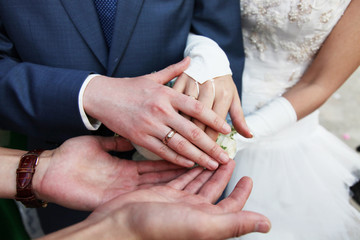 Hands of the groom and the bride with wedding rings and a wedding bouquet