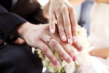 Obraz na płótnie Canvas Hands of the groom and the bride with wedding rings and a wedding bouquet