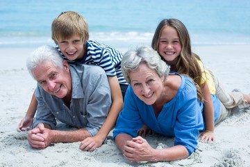 Children lying on grandparents at sea shore