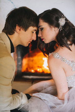happy young bride and groom sitting on the floor near fireplace