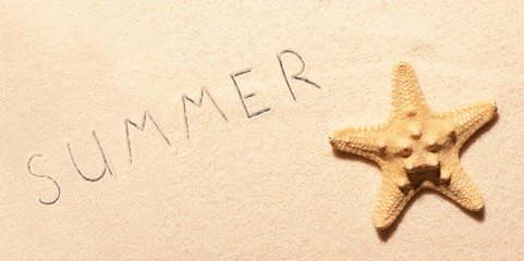 Fototapeta na wymiar Starfish on sand and summer lettering drawn on sand