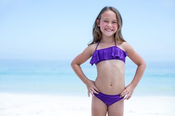 Happy girl wearing bikini standing at sea shore