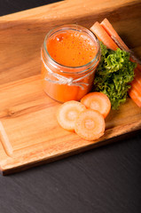 Fresh carrot smoothie in the glass on black stone. Lifestyle concept