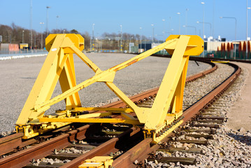 Bright yellow train buffer stop or bumper at the end of a railway track.