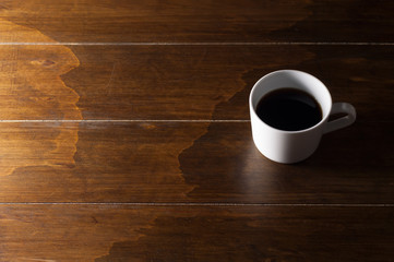 Cup of coffee on wooden brown background.